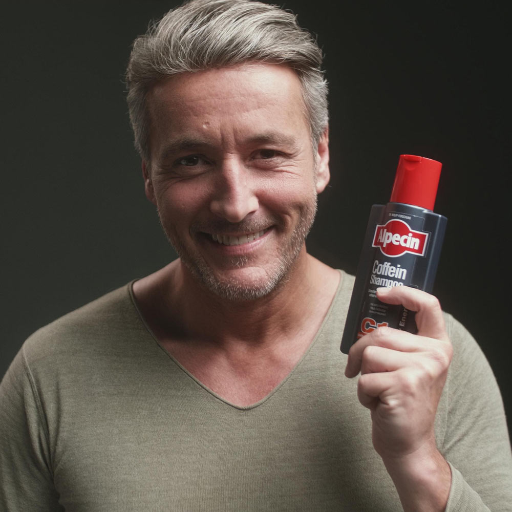 2x Alpecin Caffeine Shampoo C1 - For Stronger Hair, 375ml man holding the shampoo bottle